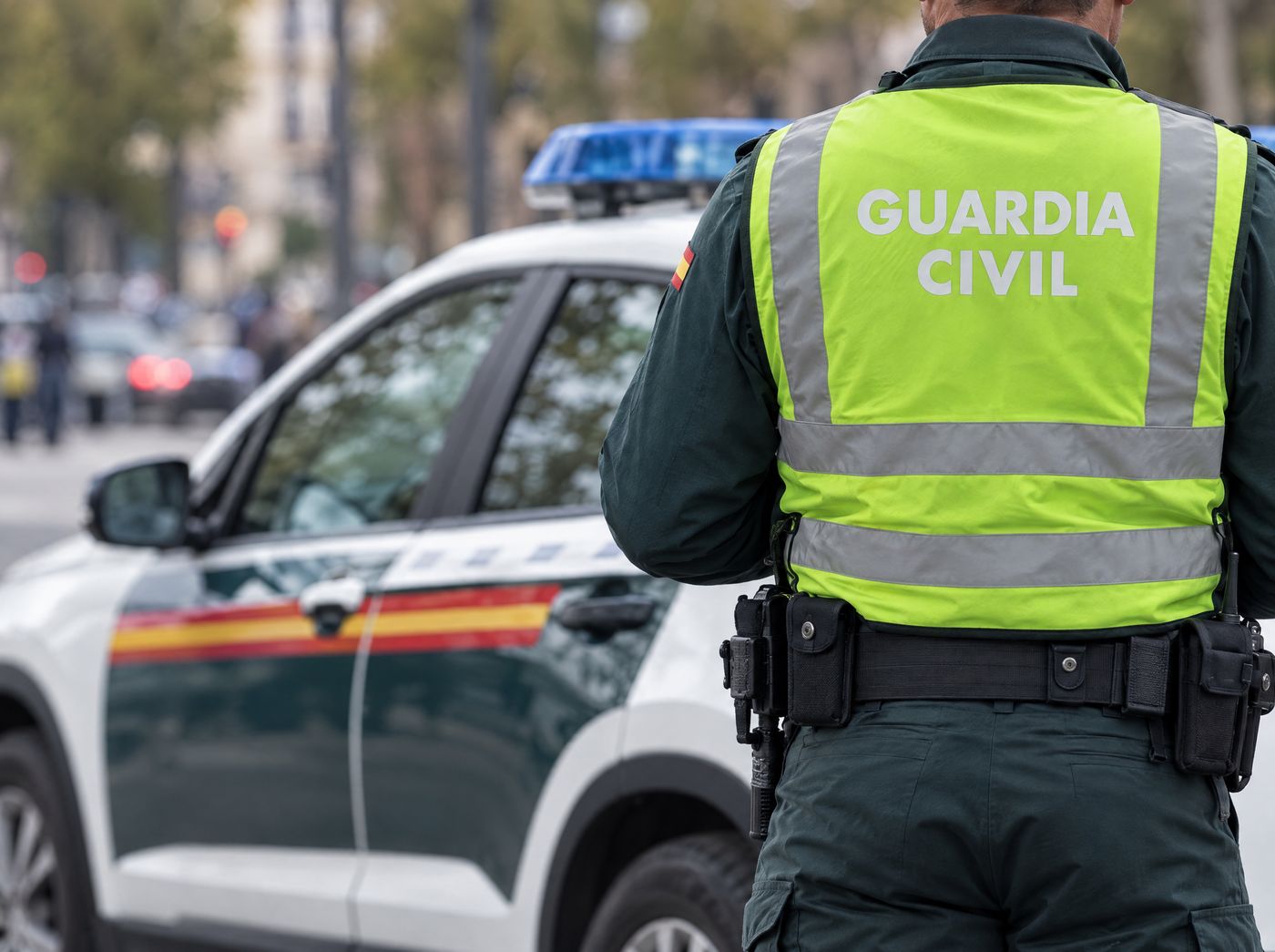 Agente de la Guardia Civil junto a un coche patrulla