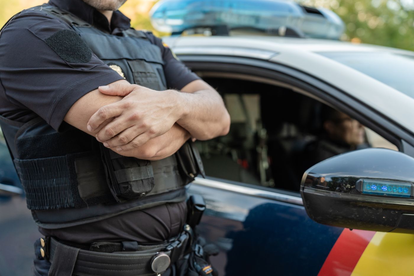 Agente de la Policía Nacional junto a un coche patrulla